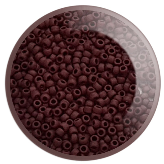 A close-up view of a small pile of round oxblood opaque frosted Toho seed beads.11/0 TR-46F