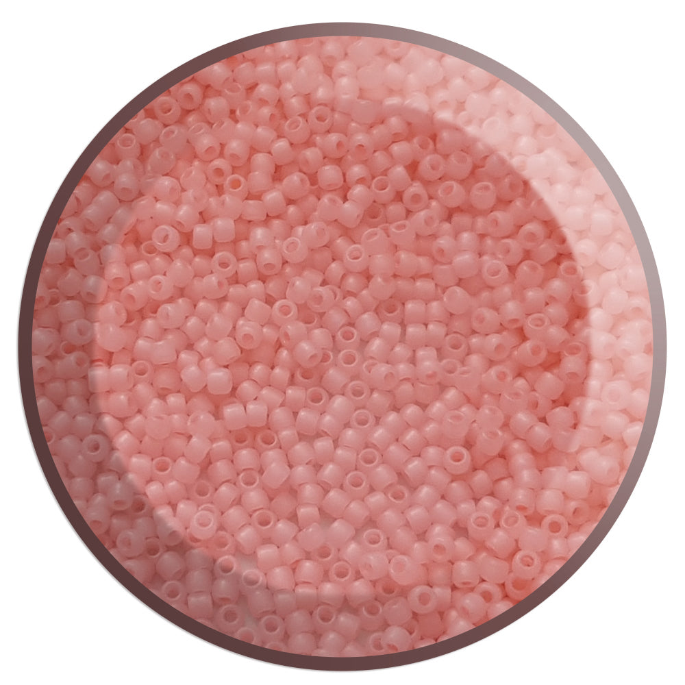 A close-up view of pink frosted round Toho seed beads.11/0 circle white background.