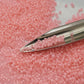 A close-up view of pink frosted round Toho seed beads.11/0 with a beading scoop