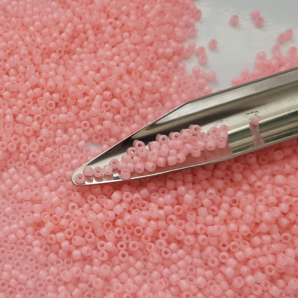A close-up view of pink frosted round Toho seed beads.11/0 with a beading scoop