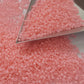 A close-up view of pink frosted round Toho seed beads.11/0  triangle scoop.