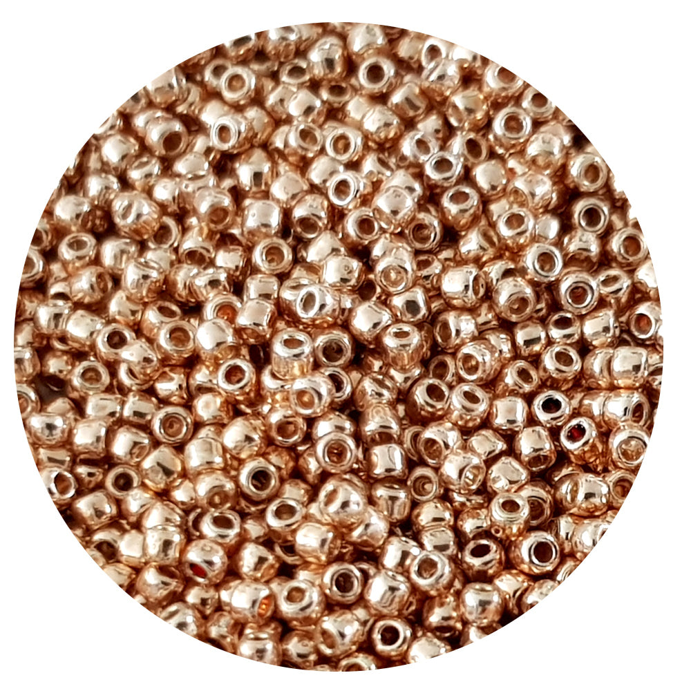 A close-up view of rose gold galvanized round Toho seed beads. 11/0 TR-PF551 in a circle white background.