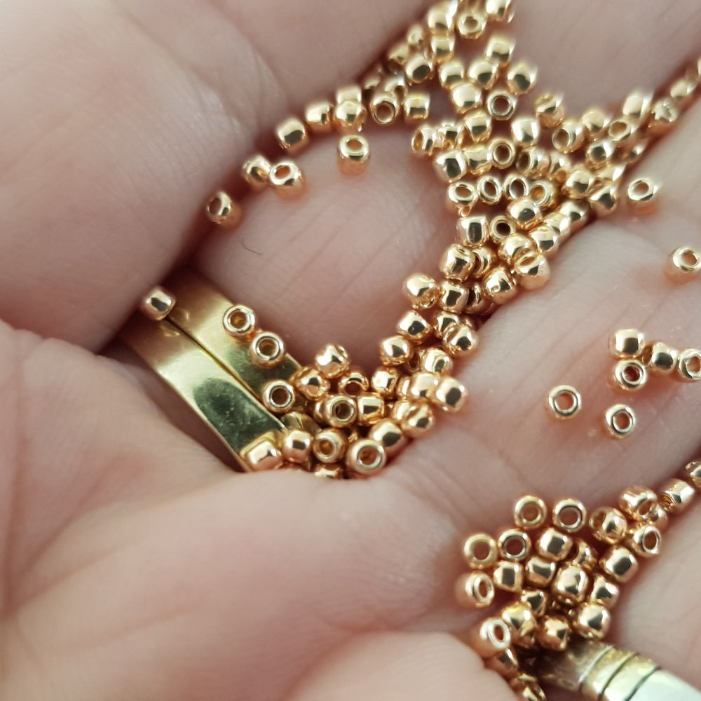 11/0 Toho Seed Beads in Rose Gold Galvanized Permanent Finish TR-PF551 close up on a hand