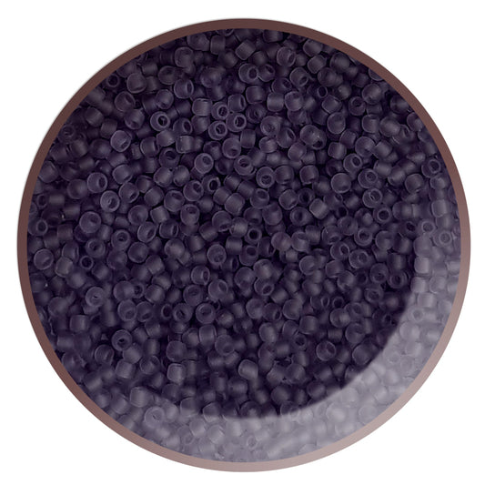 A close-up view of a bowl filled with round, frosted transparent sugar plum colored Toho seed beads in a circle white background.