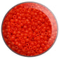 close up orange beads in a round container