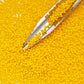 A closeup 11/0 Toho seed beads in sunshine yellow opaque frosted with beading scoop.