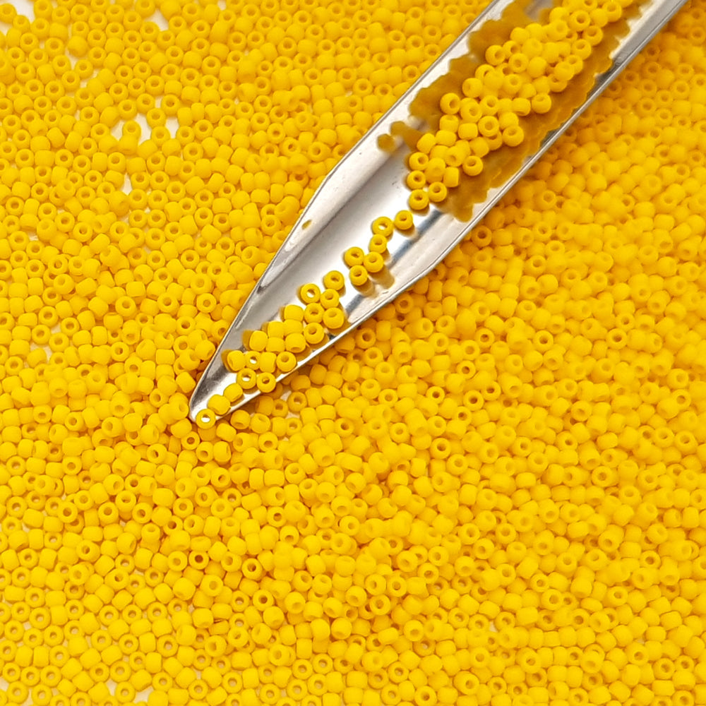A closeup 11/0 Toho seed beads in sunshine yellow opaque frosted with beading scoop.
