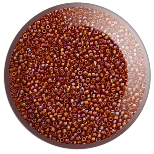 A bowl filled with round Toho seed beads in a topaz rainbow color 11/0 in a circle white background