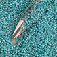11/0 Toho seed beads in turquoise opaque rainbow with a beading scoop.