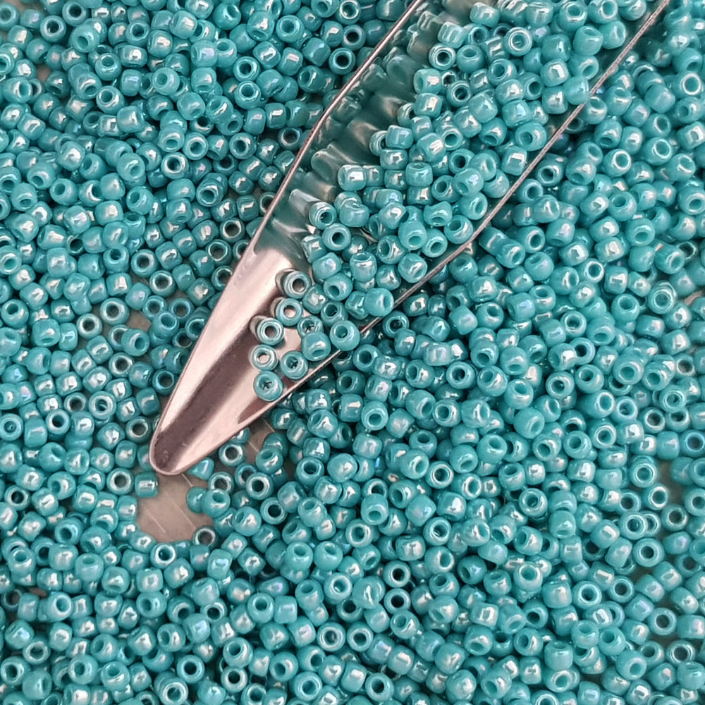 11/0 Toho seed beads in turquoise opaque rainbow with a beading scoop.