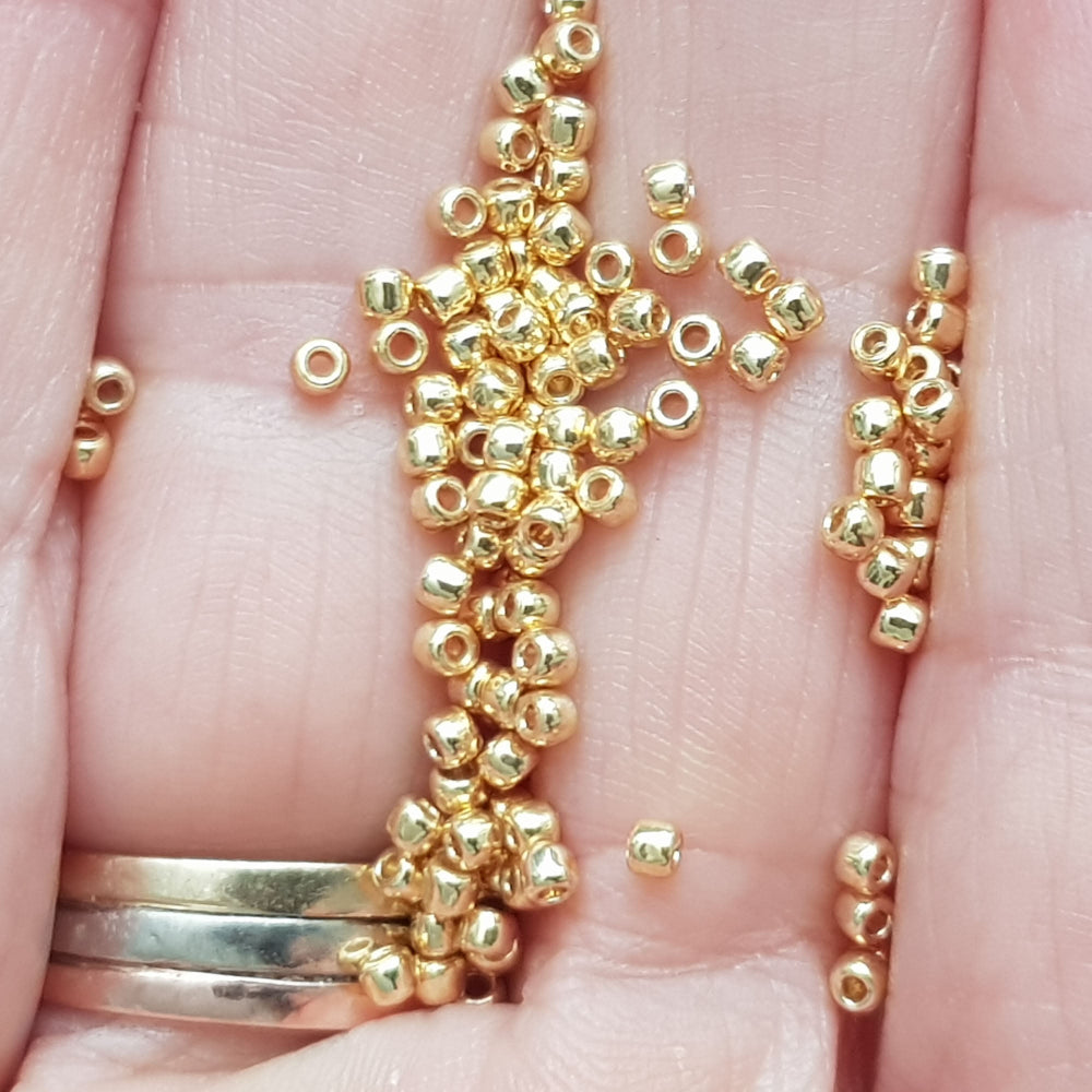 11/0 toho seed beads in starlight gold galvanized permanent finish close up on a hand.