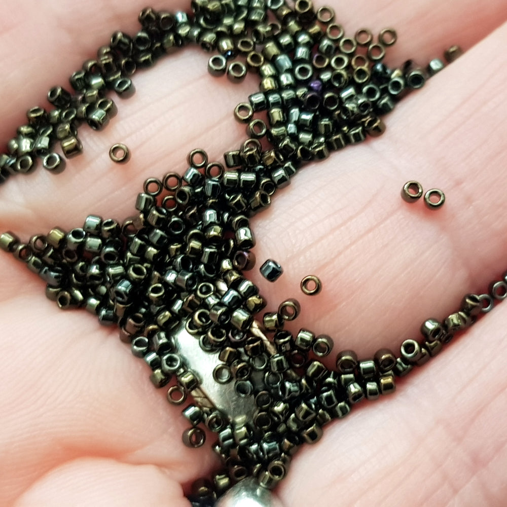 close up iris brown metallic beads on a hand.