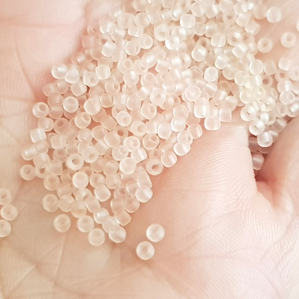 15/0 Toho Seed Beads in Rosaline Pink Frosted Transparent TR-11f on a hand.