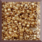 Toho 15/0 starlight gold galvanized permanent finish TR-pf557 in a square window.