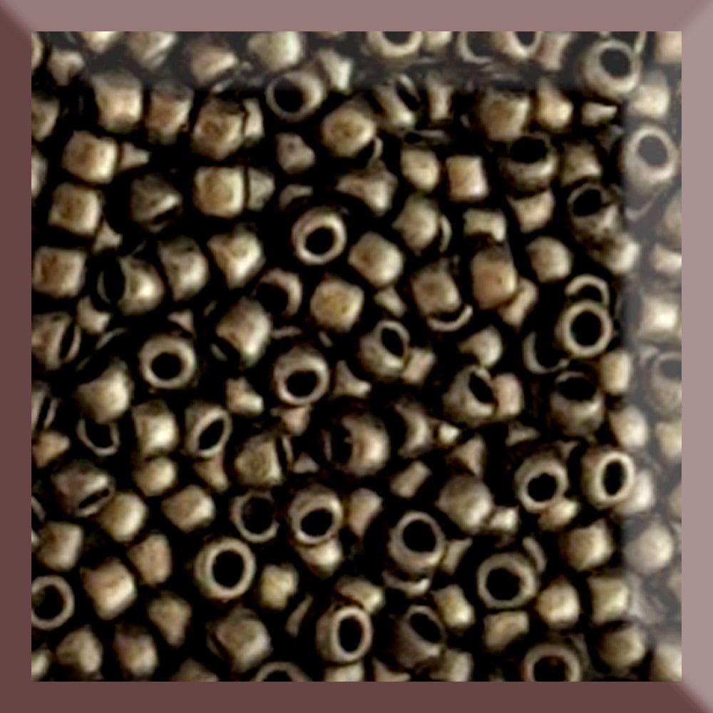 A close-up image of gold metallic round Toho seed beads with a suede hybrid finish.
