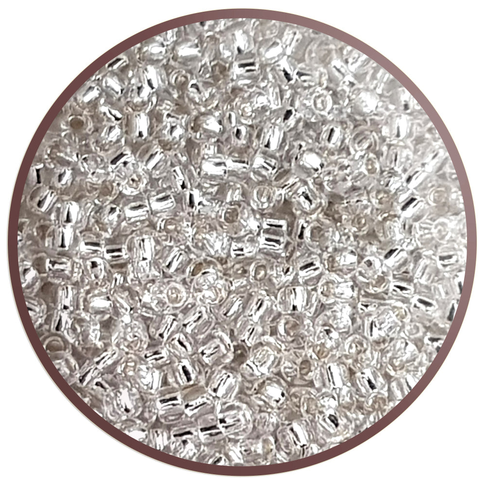 8/0 Toho Seed Beads in crystal silver-line TR-21 in a circle white background.