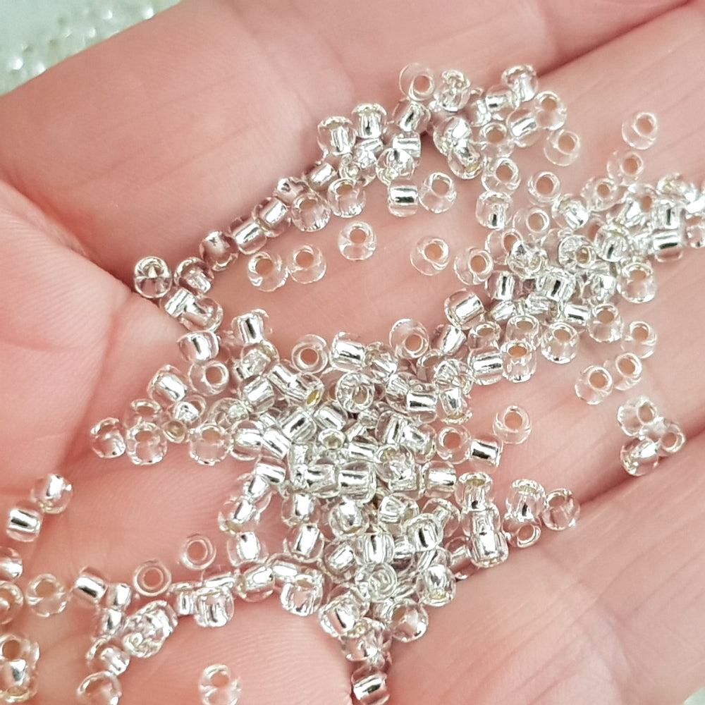8/0 Toho Seed Beads in crystal silver-lined close up on a hand.