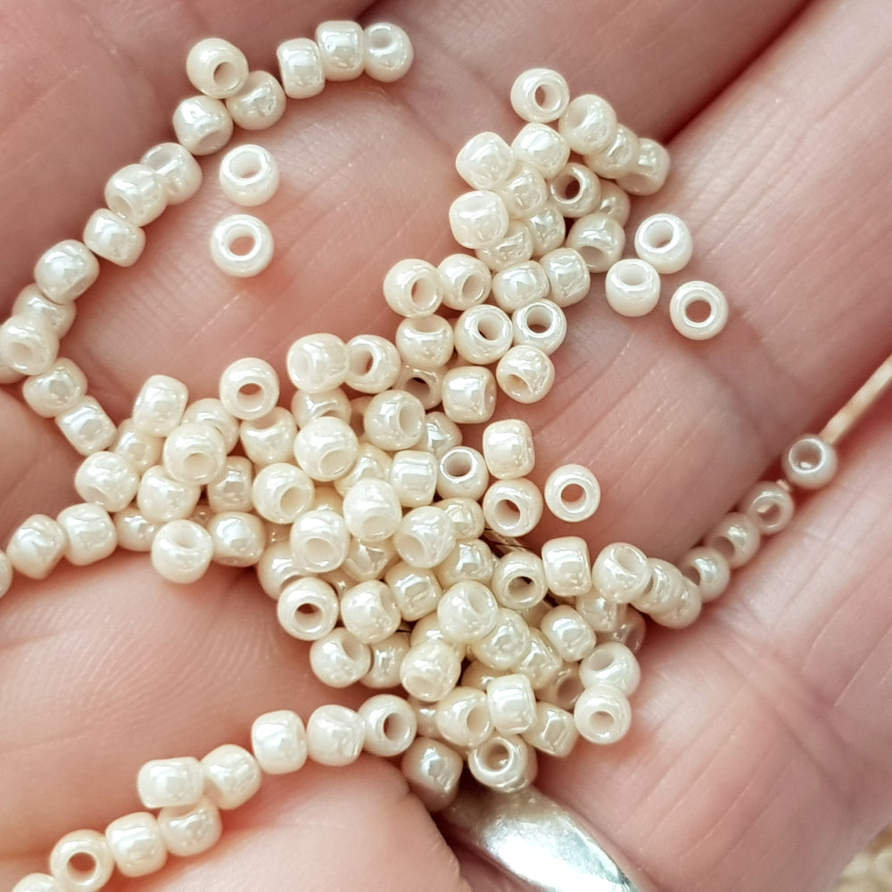 8/0. Toho seed beads in lt beige luster opaque TR-123 close up on a hand.