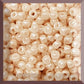 A close-up image of light beige opaque round Toho seed beads. 8/0 TR-123 square window.