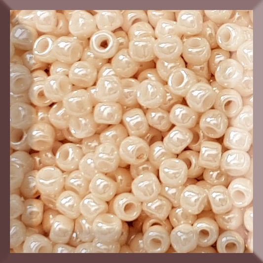 A close-up image of light beige opaque round Toho seed beads. 8/0 TR-123 square window.