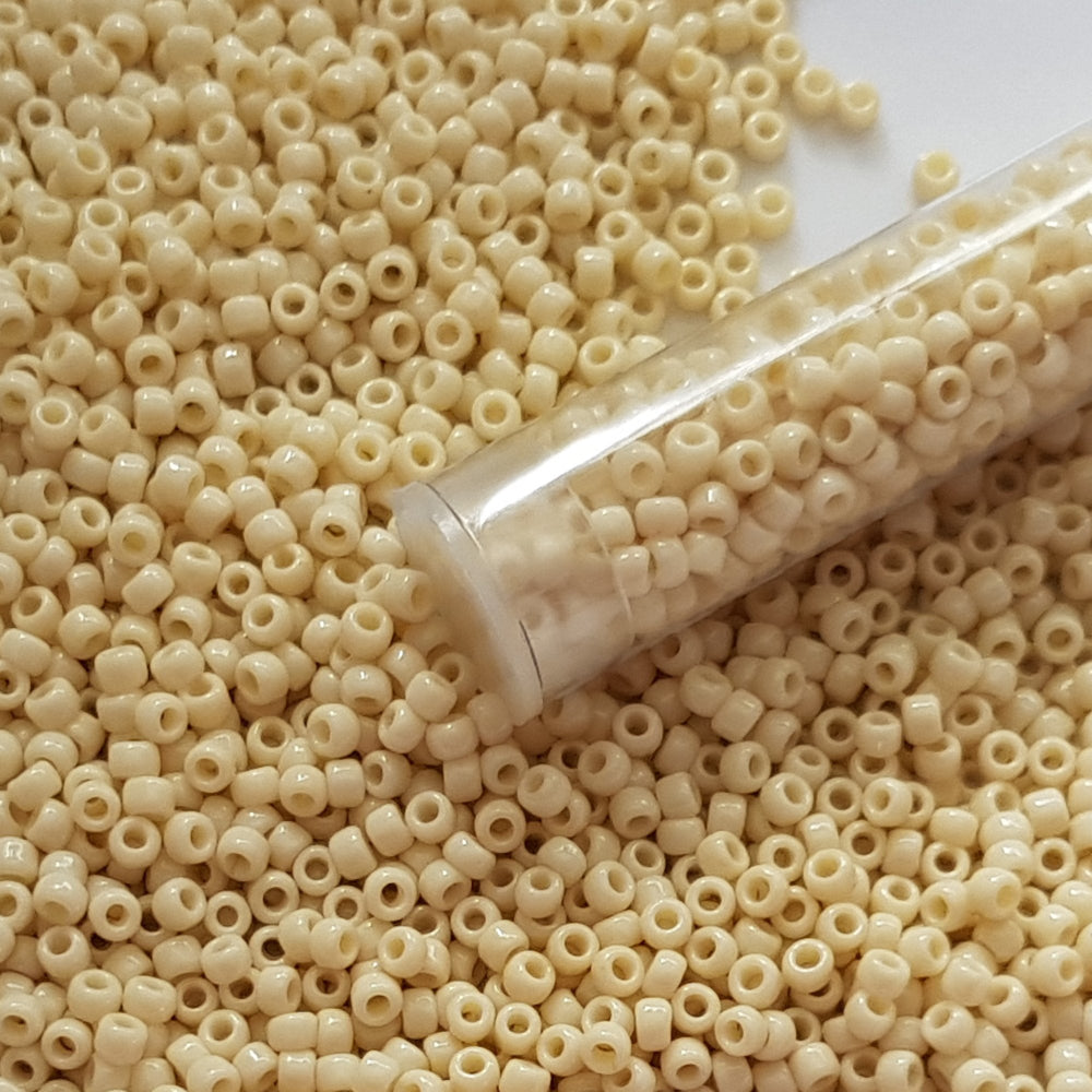8/0 TR-51 Lt Beige Opaque Round Toho Seed Beads - close up with a tube
