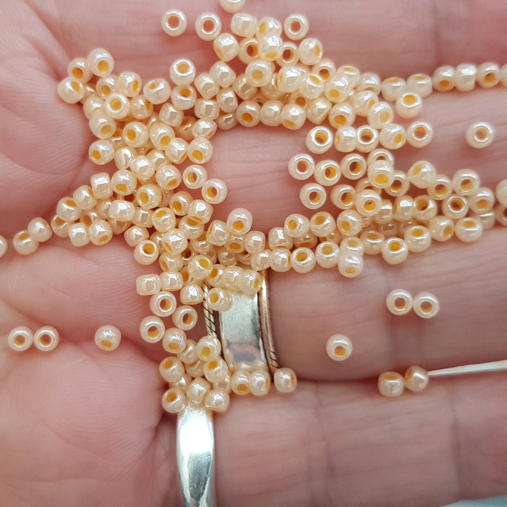 8/0 Toho Seed Bead in Peach Cobbler Ceylon TR-148 on a hand.