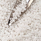 8/0 Toho Seed beads in white luster opaque with a beading scoop.