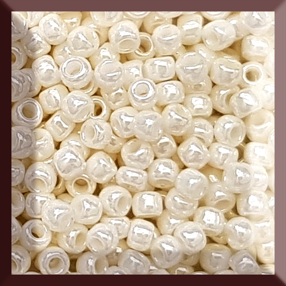 A close-up image of white opaque round Toho seed beads. 8/0 TR-122 square window.