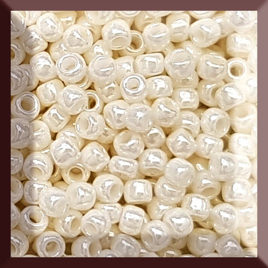 A close-up image of white opaque round Toho seed beads. 8/0 TR-122 square window.