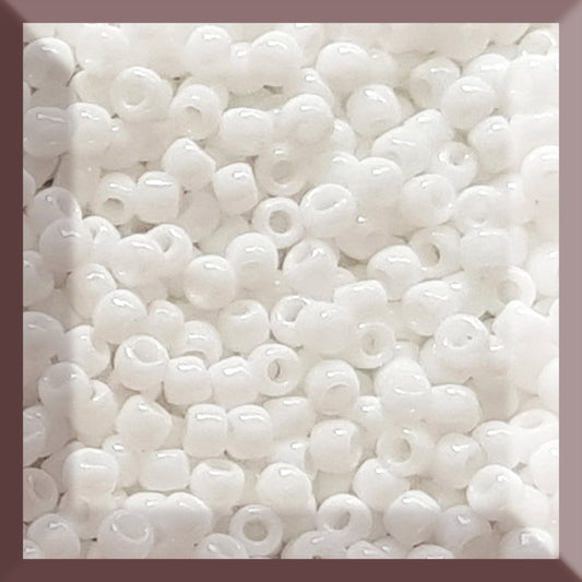 A close-up image of white opaque round Toho seed beads Square window.