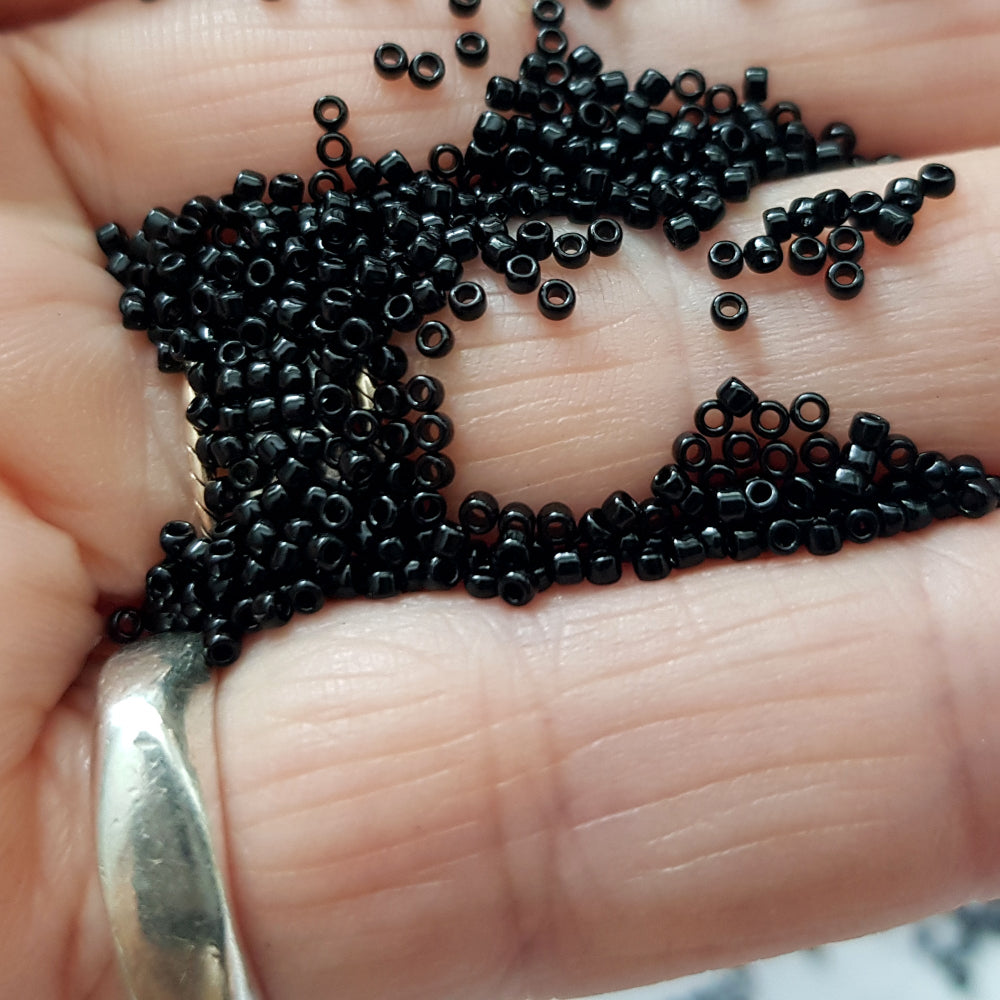 Toho seed beads 15/0 jet black opaque TR-49 in a hand.
